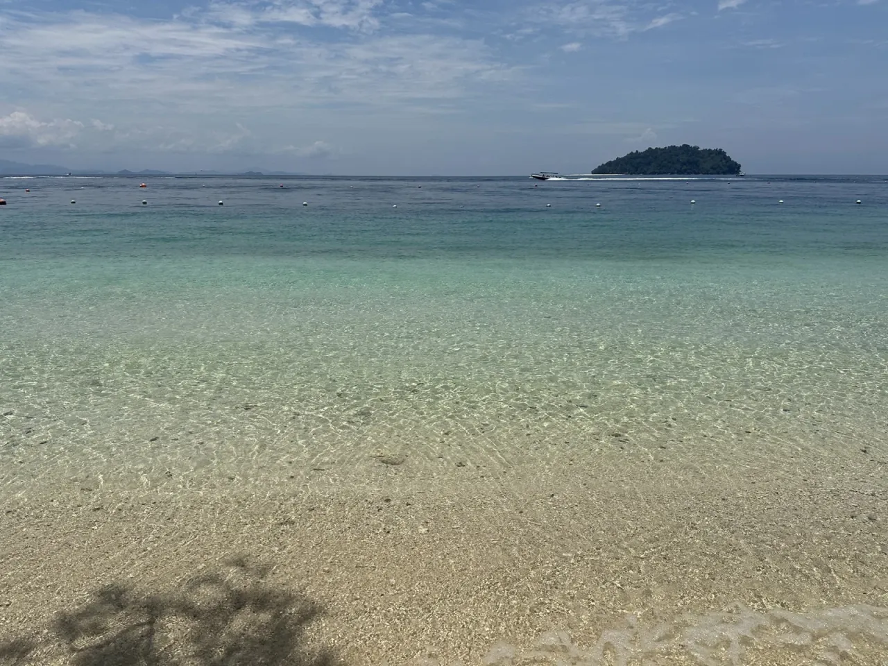 マヌカン島の透明な浅瀬と沖を走るボート
